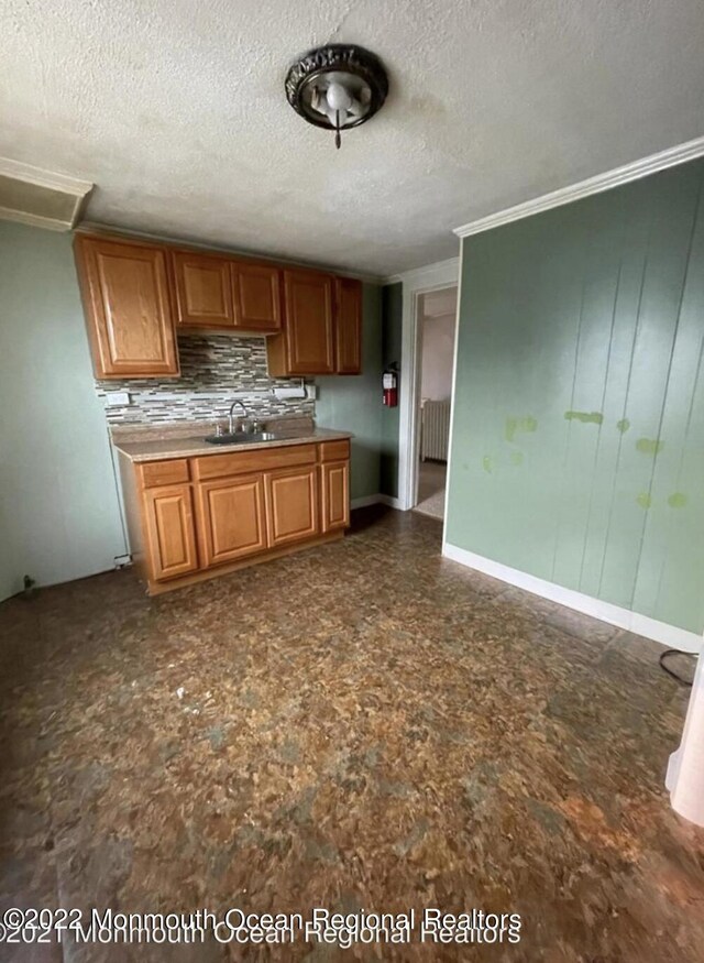 kitchen featuring a textured ceiling, crown molding, radiator, and tasteful backsplash