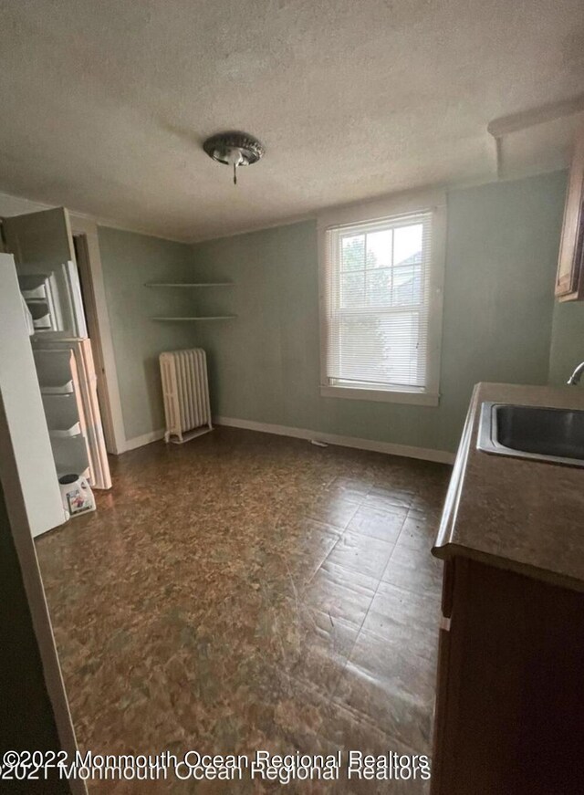 unfurnished bedroom with radiator heating unit, a textured ceiling, and sink