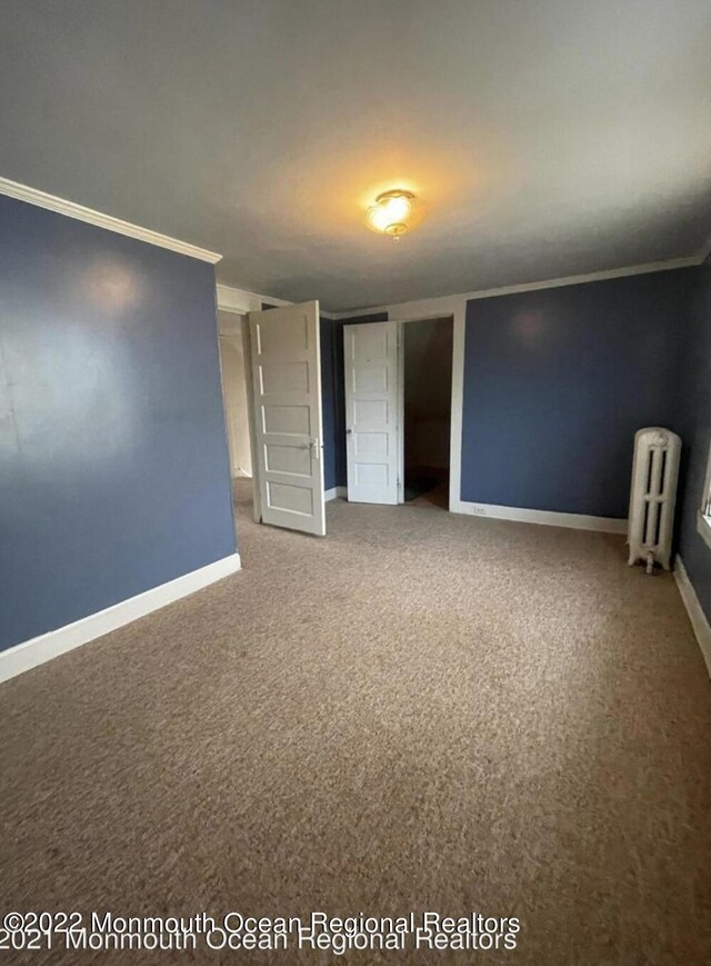 unfurnished bedroom featuring radiator heating unit, ornamental molding, and carpet flooring