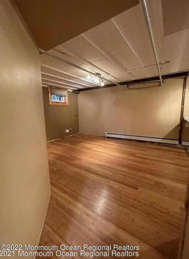 basement with hardwood / wood-style floors and a baseboard radiator