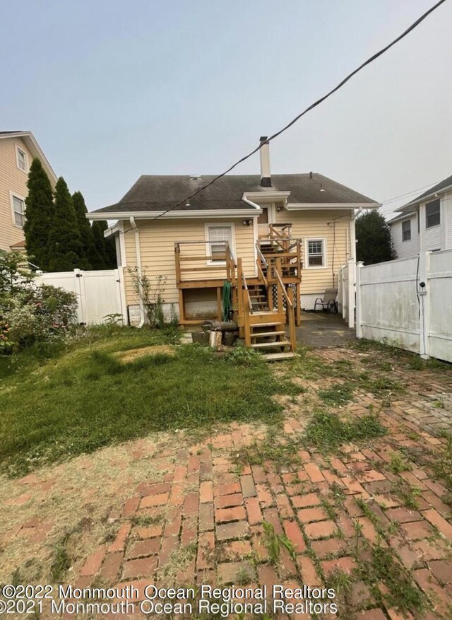 back of property with a yard and a deck