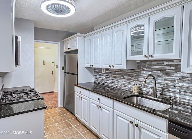 kitchen featuring dark stone countertops, white cabinetry, sink, appliances with stainless steel finishes, and light tile patterned flooring