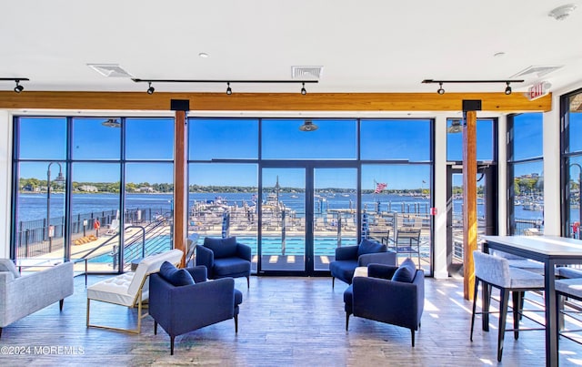 living room with track lighting, a water view, and hardwood / wood-style floors