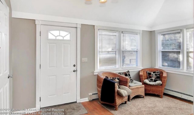 entryway with vaulted ceiling, a baseboard heating unit, and light hardwood / wood-style floors