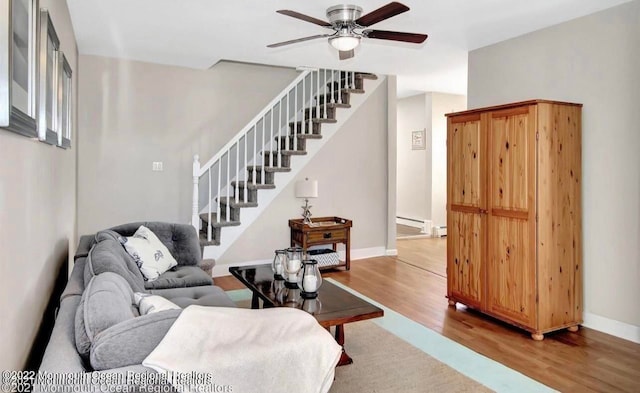 living room with baseboard heating, light hardwood / wood-style flooring, and ceiling fan