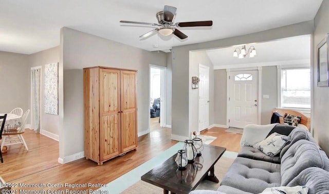 living room featuring ceiling fan with notable chandelier and light hardwood / wood-style floors