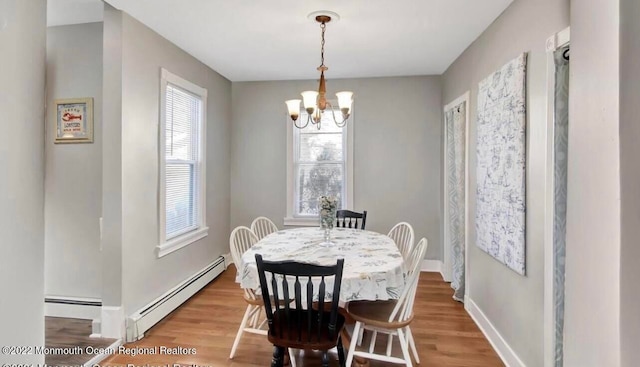 dining room with a baseboard radiator, hardwood / wood-style floors, and an inviting chandelier