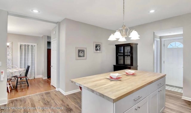 kitchen featuring butcher block counters, white cabinetry, a kitchen island, and light wood-type flooring