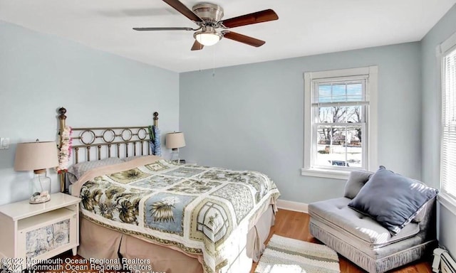 bedroom featuring a baseboard radiator, light wood-type flooring, and ceiling fan