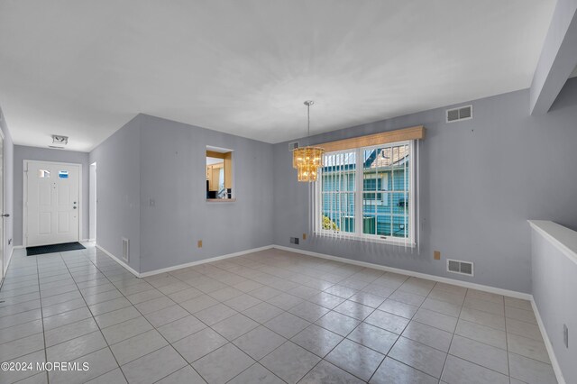 unfurnished room with light tile patterned floors and a notable chandelier