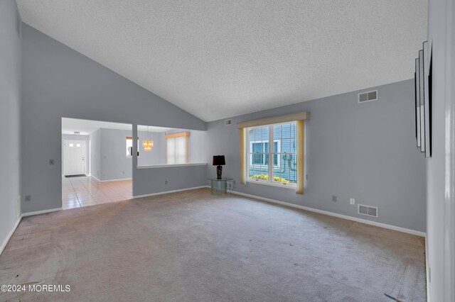 carpeted spare room featuring high vaulted ceiling and a textured ceiling