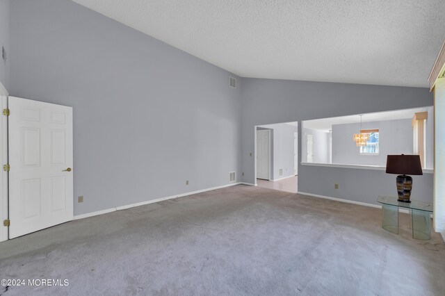 unfurnished living room featuring a textured ceiling, carpet, a notable chandelier, and high vaulted ceiling