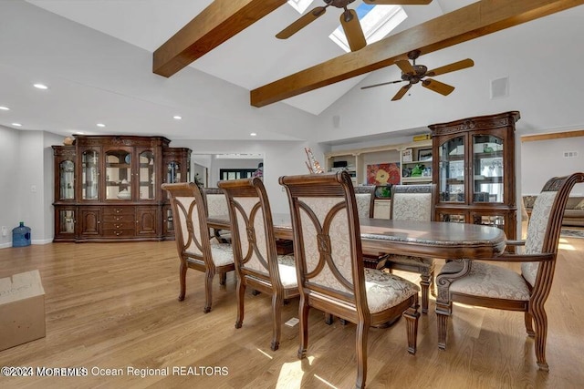 dining room featuring light hardwood / wood-style floors, high vaulted ceiling, beamed ceiling, ceiling fan, and a skylight