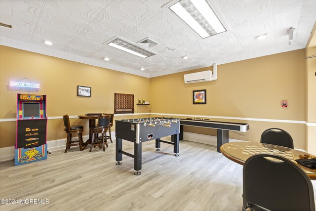 game room with light hardwood / wood-style flooring and a wall mounted AC