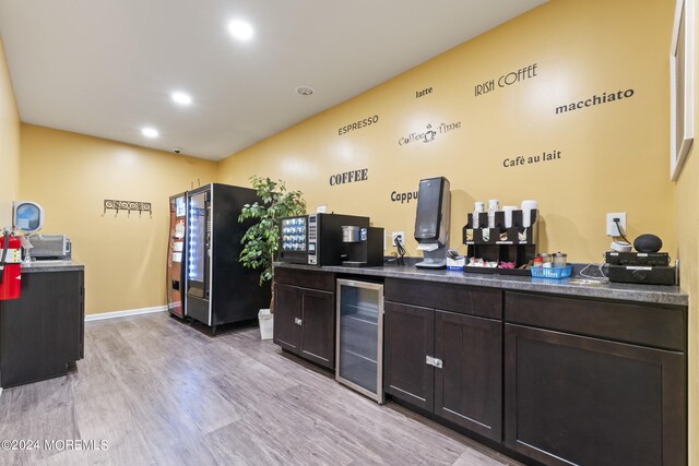 kitchen featuring stainless steel refrigerator, dark brown cabinetry, beverage cooler, and light hardwood / wood-style flooring