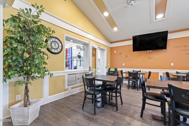 dining space with hardwood / wood-style flooring, vaulted ceiling, and ornamental molding