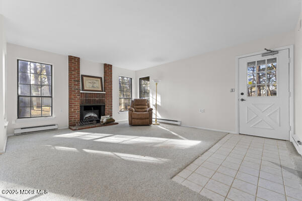 unfurnished living room featuring a brick fireplace, light colored carpet, and baseboard heating