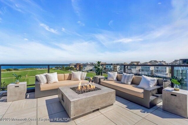 view of patio with an outdoor living space with a fire pit and a water view