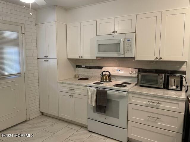 kitchen with a toaster, decorative backsplash, white appliances, and white cabinetry