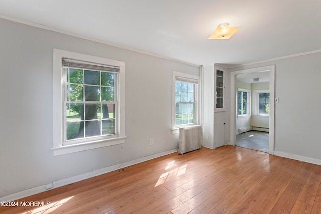 unfurnished bedroom featuring ornamental molding, radiator, baseboard heating, and light hardwood / wood-style flooring