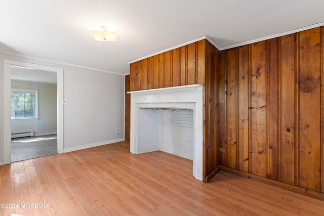 unfurnished living room featuring light wood-type flooring, crown molding, wooden walls, and baseboard heating