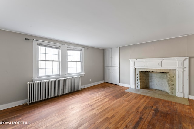 unfurnished living room featuring radiator and wood-type flooring