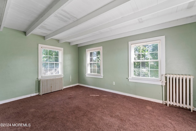 spare room with radiator heating unit, dark carpet, and a healthy amount of sunlight