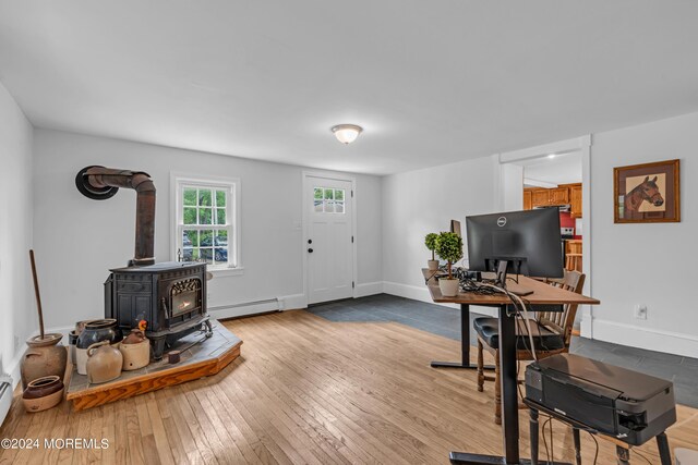 home office with light wood-type flooring, a wood stove, and baseboard heating