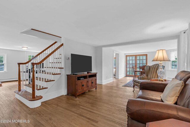 living room with a baseboard heating unit, plenty of natural light, and light hardwood / wood-style flooring