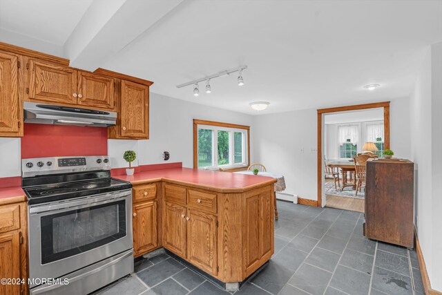 kitchen with dark tile patterned flooring, a baseboard heating unit, kitchen peninsula, and stainless steel range with electric cooktop