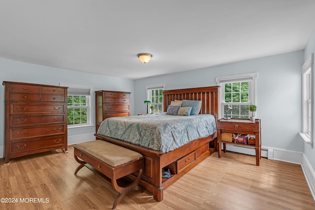 bedroom with baseboard heating and light hardwood / wood-style floors