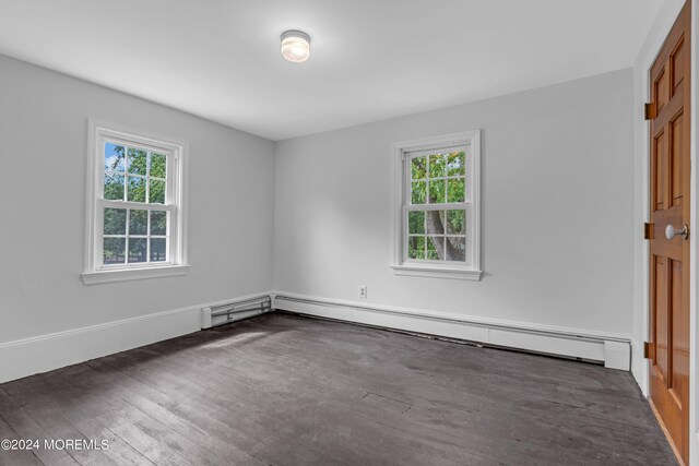 unfurnished room with dark wood-type flooring and baseboard heating