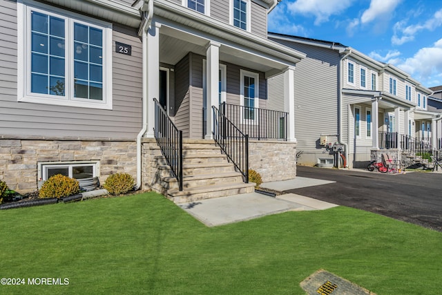 property entrance featuring covered porch and a lawn