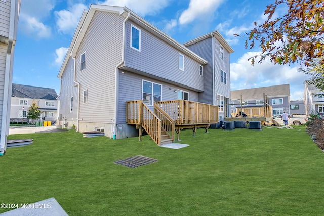 rear view of property featuring central air condition unit, a deck, and a lawn