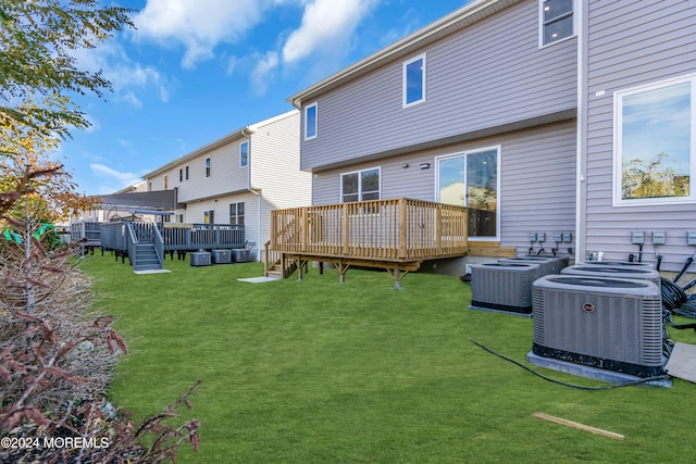 back of property with central air condition unit, a lawn, and a wooden deck