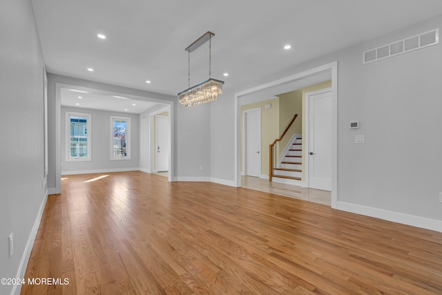 unfurnished living room with light hardwood / wood-style floors and a notable chandelier