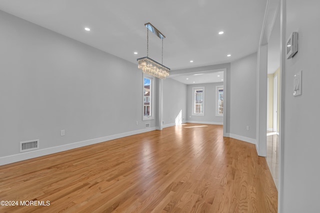 unfurnished living room featuring light hardwood / wood-style floors and an inviting chandelier