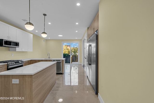 kitchen with appliances with stainless steel finishes, sink, a center island, decorative light fixtures, and white cabinets