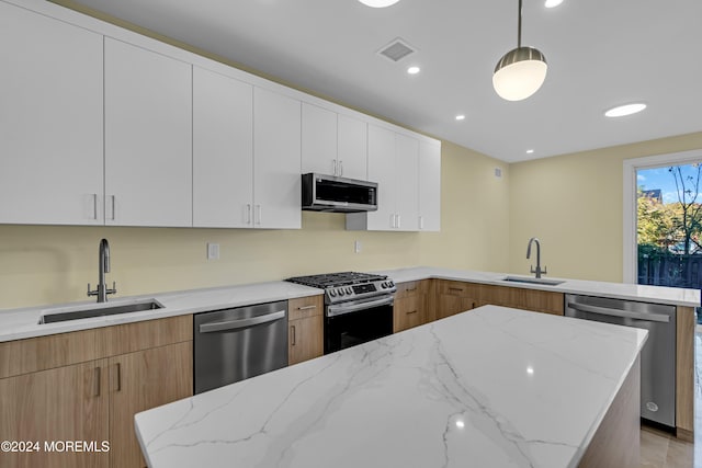 kitchen featuring white cabinets, stainless steel appliances, sink, and decorative light fixtures