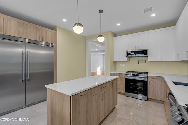 kitchen with a kitchen island, stainless steel appliances, decorative light fixtures, white cabinets, and light stone counters