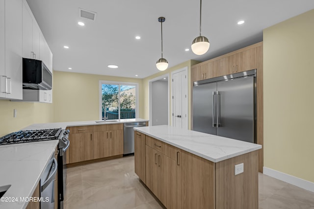 kitchen with light stone countertops, appliances with stainless steel finishes, a center island, white cabinetry, and decorative light fixtures