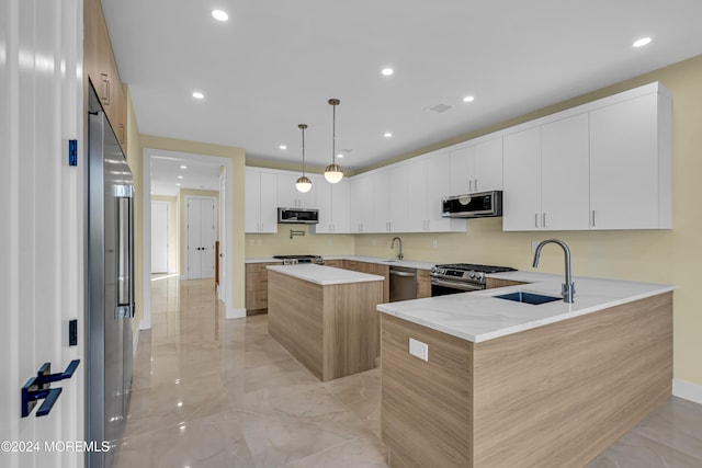 kitchen featuring sink, appliances with stainless steel finishes, decorative light fixtures, and white cabinets