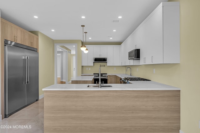 kitchen with light brown cabinets, kitchen peninsula, hanging light fixtures, white cabinetry, and stainless steel appliances