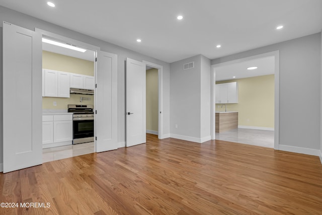 kitchen with stainless steel range, light hardwood / wood-style floors, and white cabinets