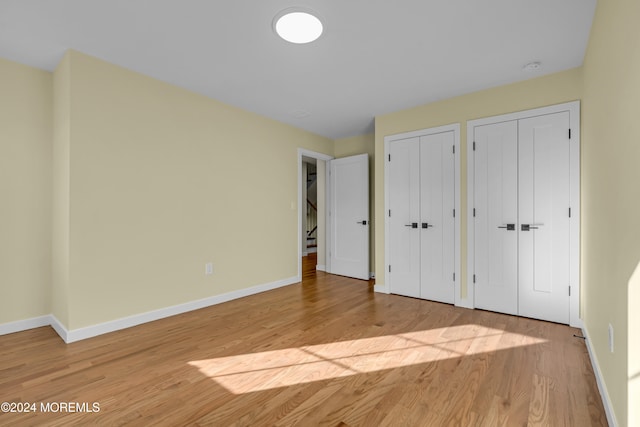 unfurnished bedroom with multiple closets and light wood-type flooring