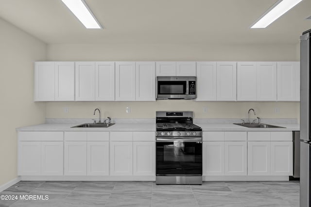 kitchen with sink, appliances with stainless steel finishes, and white cabinetry