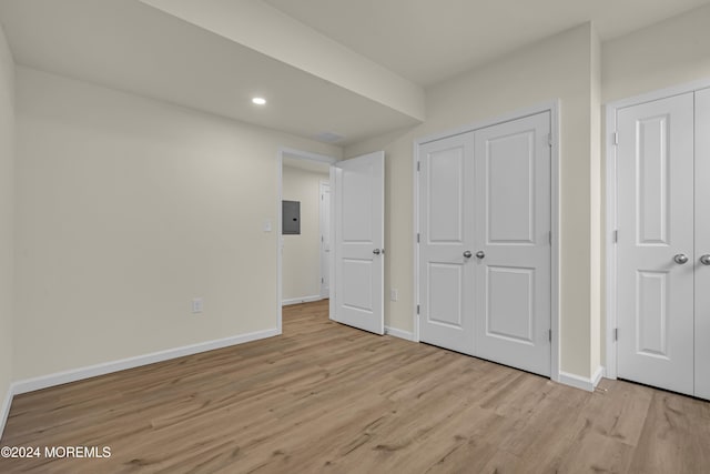 unfurnished bedroom featuring electric panel and light hardwood / wood-style floors