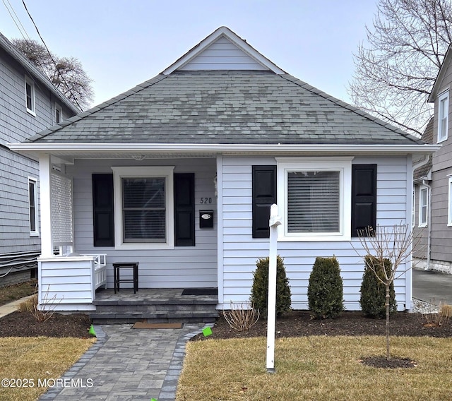 bungalow-style house featuring covered porch and a front yard