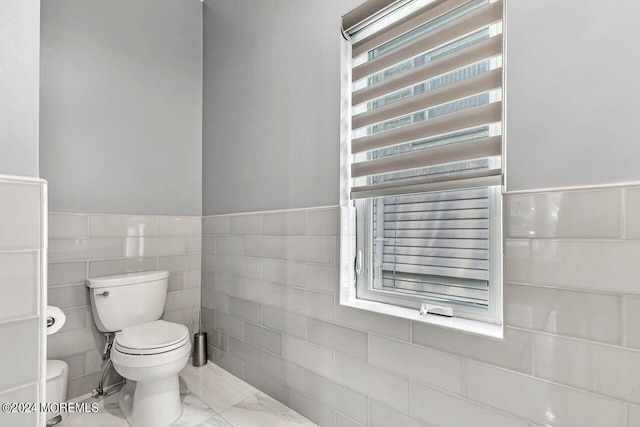 bathroom featuring tile walls and toilet