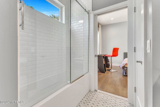 bathroom featuring wood-type flooring and bath / shower combo with glass door